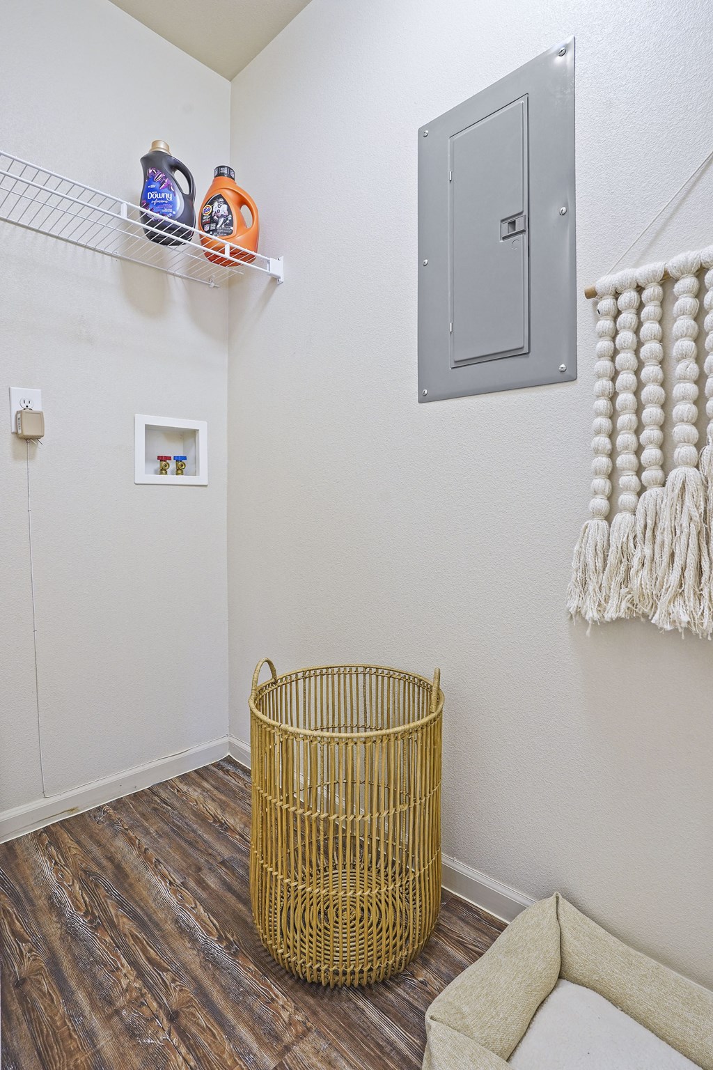A room with a basket on the floor and a shelf above it.