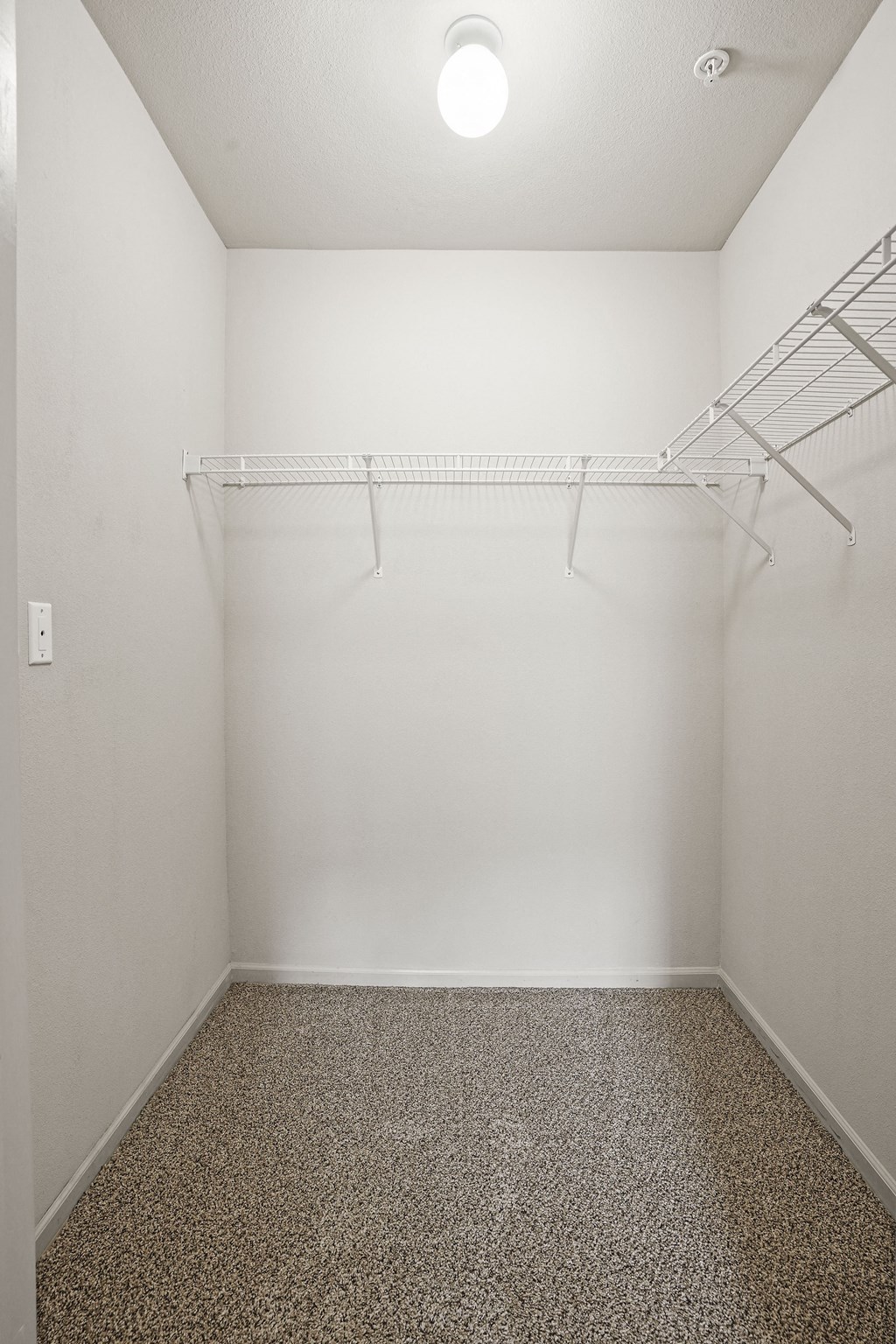 Empty room with a shelf and a light on the ceiling.