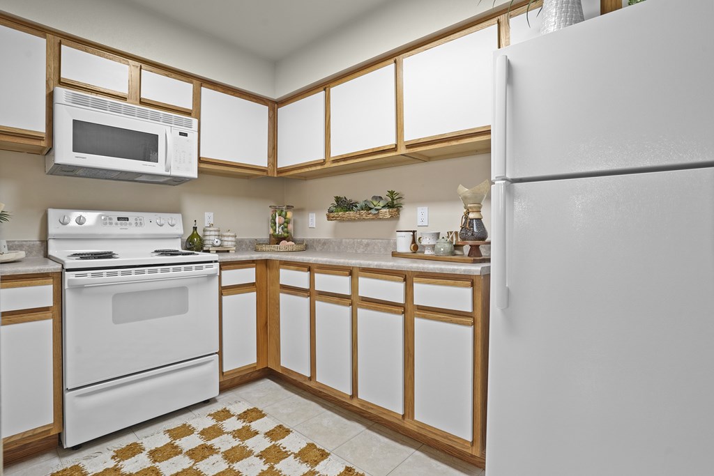 A kitchen with white appliances and wooden cabinets.