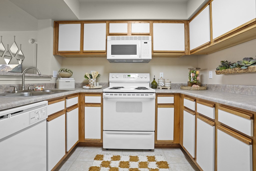 A kitchen with white appliances and wooden cabinets.