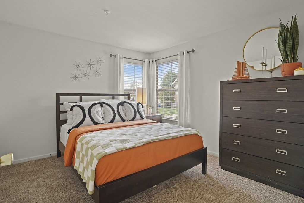 A bedroom with a bed, dresser, and window.