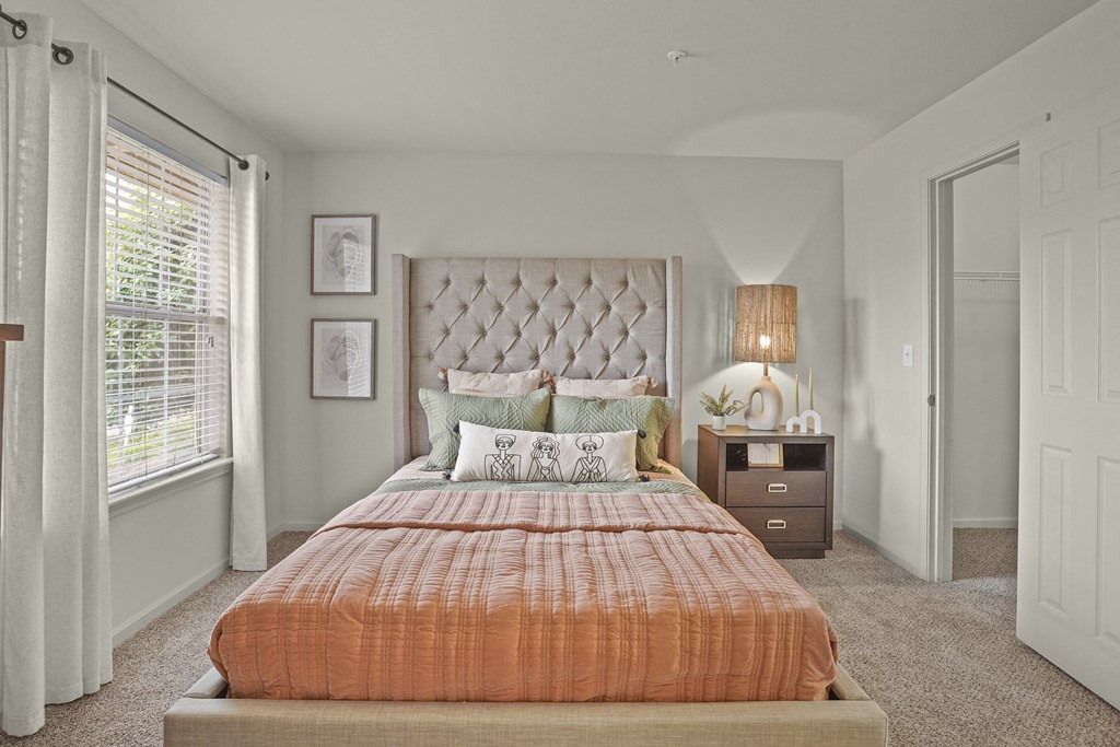 A bedroom with a large bed and a window with curtains.