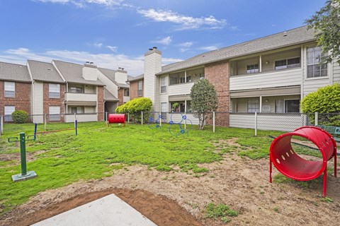A playground area with a red slide and a red chair in the foreground.