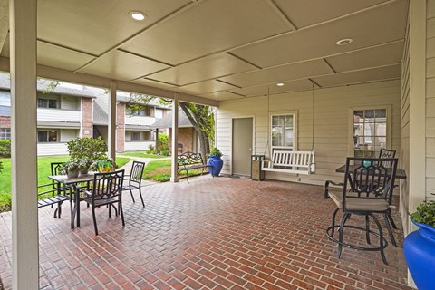 A patio with a table and chairs is covered by a roof.