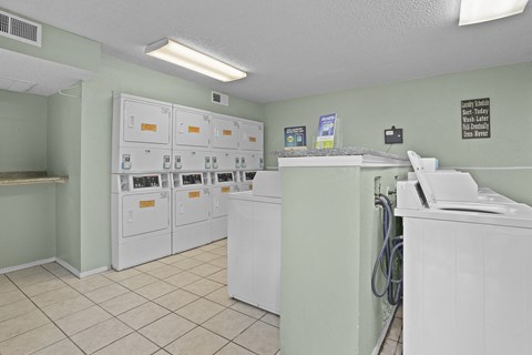 A laundromat with washers and dryers lined up against the wall.