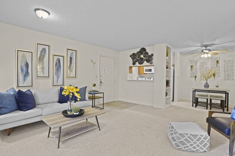 A living room with a white couch, a coffee table, and a ceiling fan.