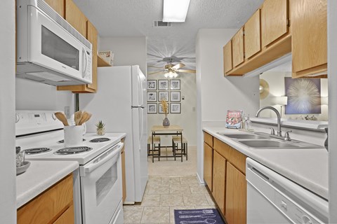 A kitchen with white appliances and wooden cabinets.