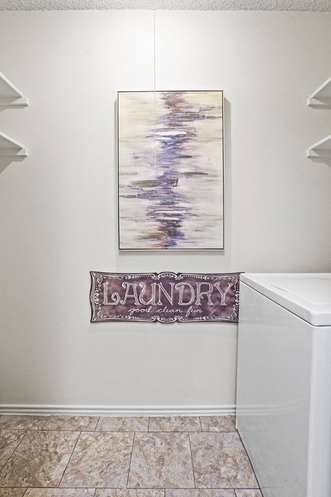 Laundry sign hanging on a wall next to a washing machine.