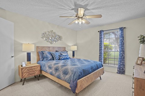 A bedroom with a bed, nightstands, and a ceiling fan.