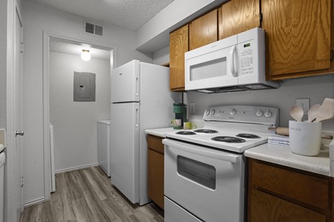 A kitchen with a white refrigerator, white stove, and wooden cabinets.
