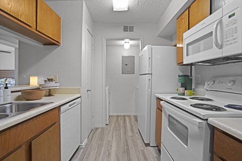 A kitchen with white appliances and wooden cabinets.