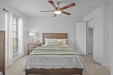 A bedroom with a bed, nightstand, and a ceiling fan.
