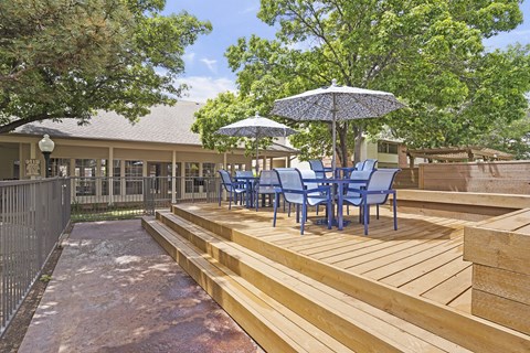 A patio with blue chairs and an umbrella.