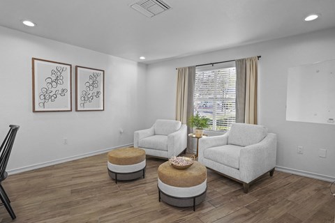 A living room with two chairs and two ottomans.