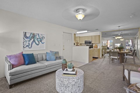 A living room with a grey couch and a painting on the wall.