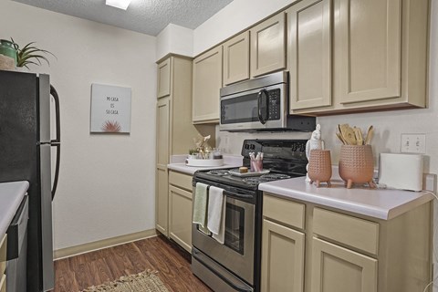 A kitchen with beige cabinets and a black stove top.