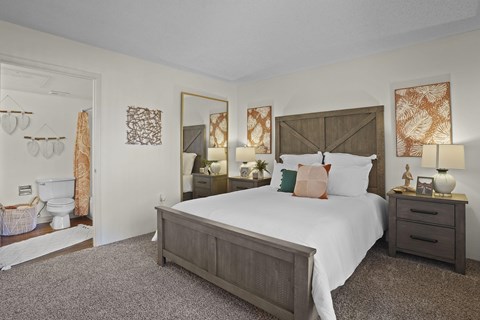 A bedroom with a large bed, nightstands, and a mirror.