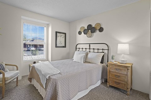 A bedroom with a bed, nightstand, and chair.