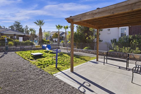 A patio area with a wooden pergola and a bench.