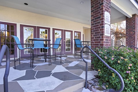 A patio with a table and chairs and a brick pillar.