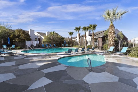 A pool surrounded by palm trees and lounge chairs.