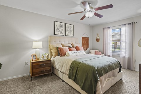 A bedroom with a large bed and a ceiling fan.