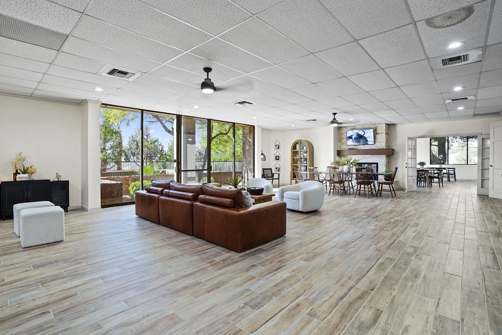 A spacious living room with a brown leather couch and a white ottoman.