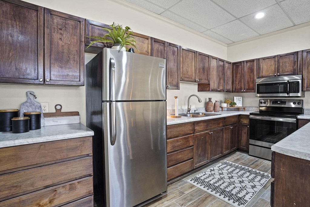 A kitchen with a stainless steel refrigerator and wooden cabinets.