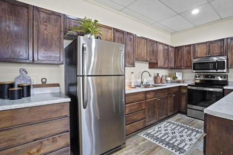 A kitchen with a stainless steel refrigerator and wooden cabinets.