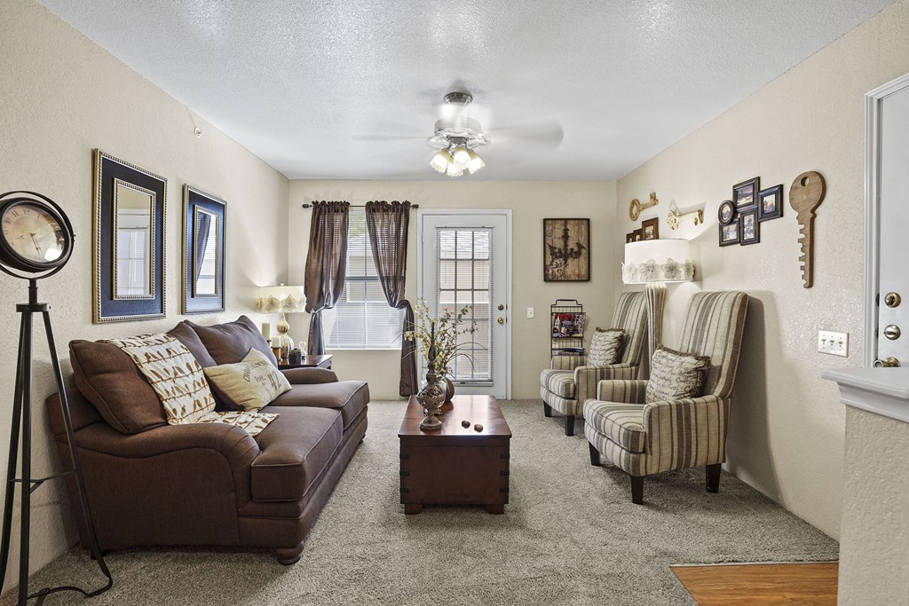A living room with a brown couch, two chairs, and a coffee table.