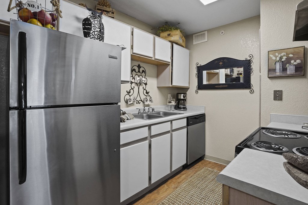 A kitchen with a stainless steel refrigerator and white cabinets.