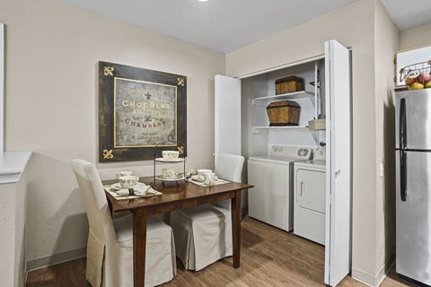 A kitchen with a table set for two and a chocolate cabinet.
