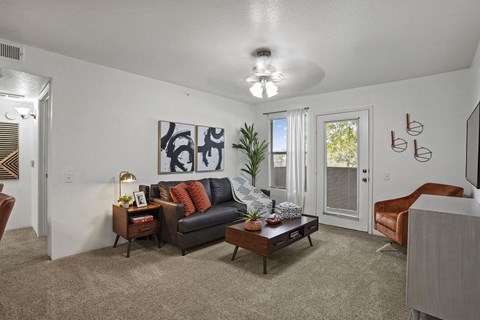 A living room with a black couch and a painting on the wall.