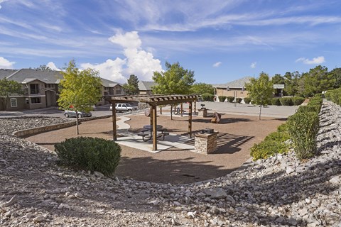 A sunny day at the park with a playground and a picnic table.
