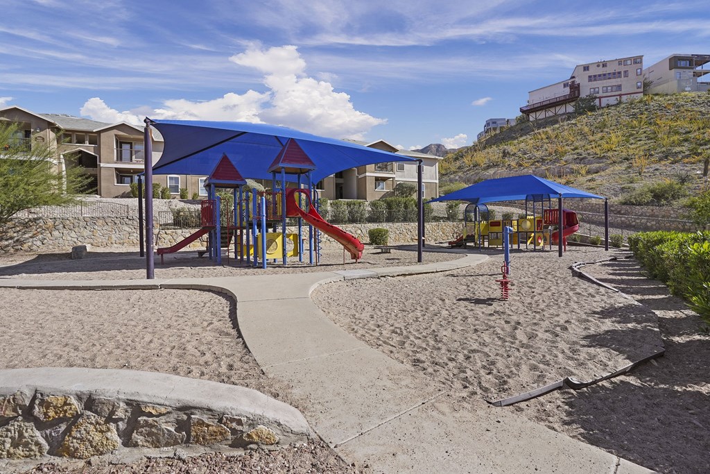 A playground with a blue canopy and a red slide.