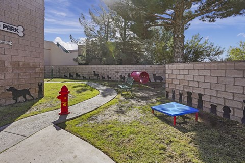 A dog is standing next to a red fire hydrant in a park.