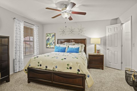 A bedroom with a large bed and a ceiling fan.
