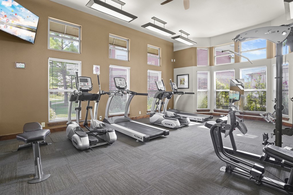 A gym with treadmills, elliptical machines, and other exercise equipment.