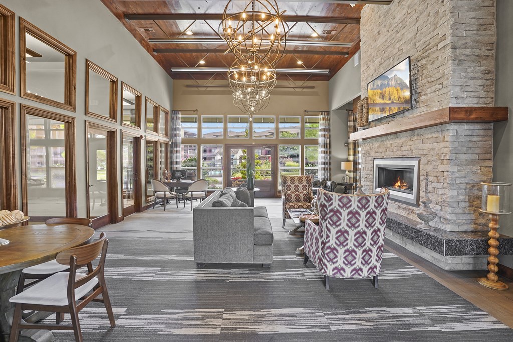 A large, well-lit living room with a stone fireplace and a chandelier.