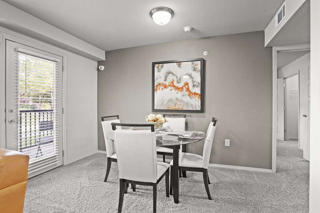 A dining room with a table set for two and a painting on the wall.