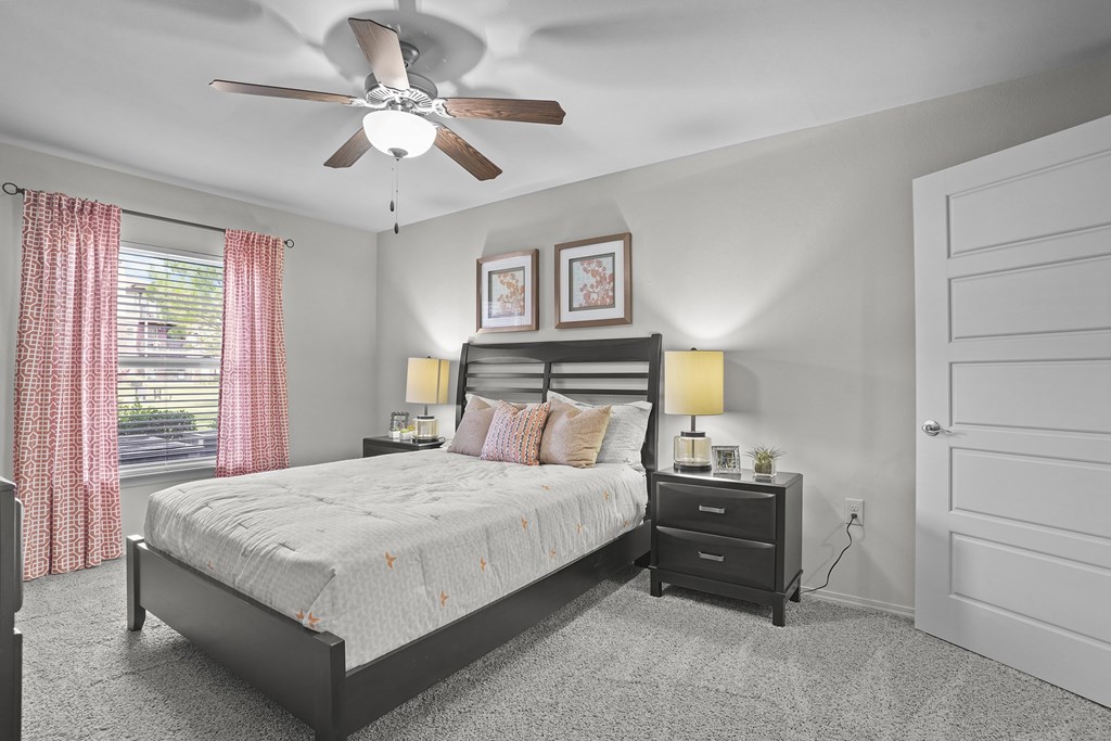 A bedroom with a bed, nightstands, and a ceiling fan.