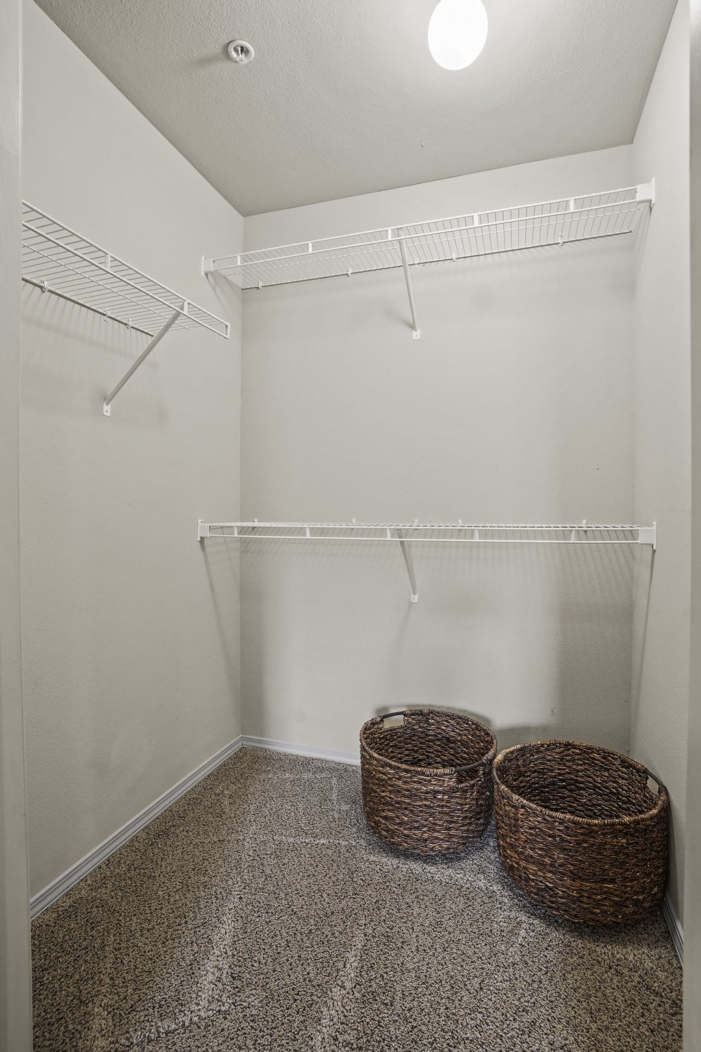 A laundry room with a white wall and a white shelf.