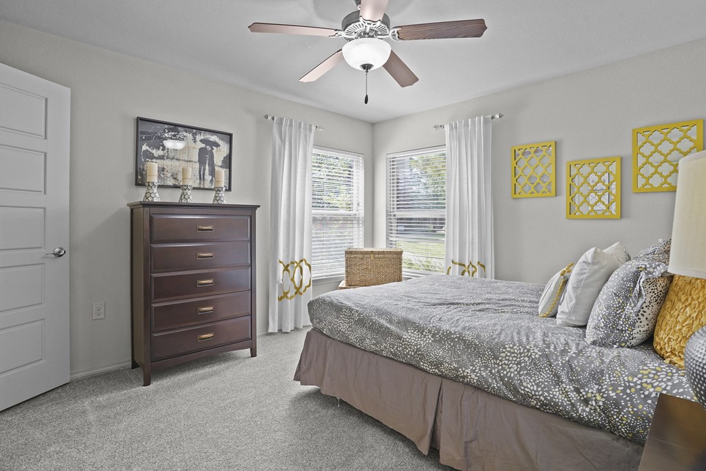 A bedroom with a bed, dresser, and window.