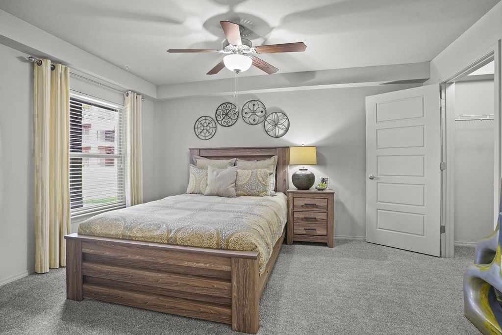 A bedroom with a bed, nightstand, and a ceiling fan.