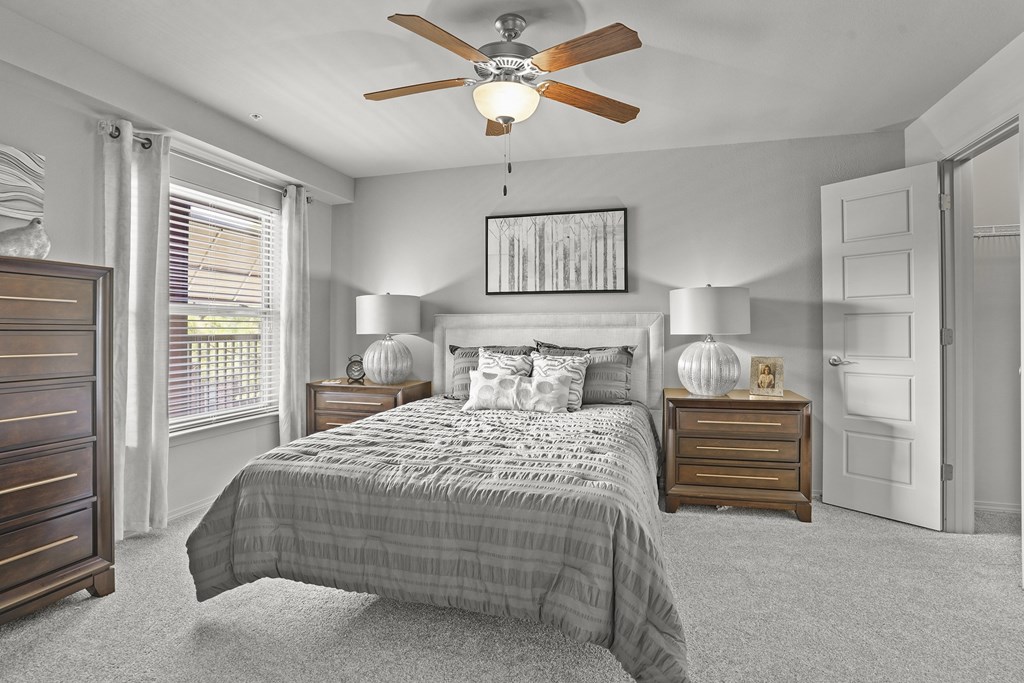 A bedroom with a bed, nightstands, and a ceiling fan.