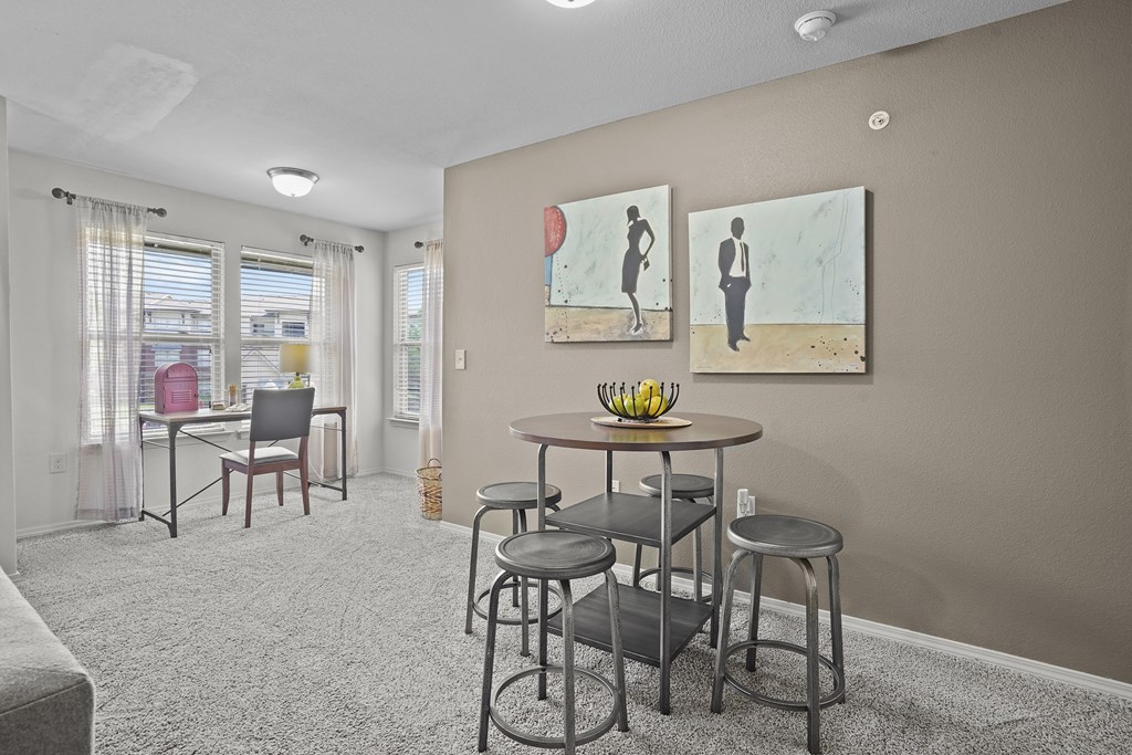 A living room with a grey carpet and a painting of a man on the wall.