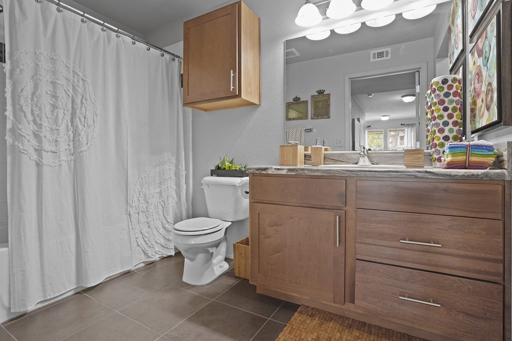 A bathroom with a toilet, sink, and shower curtain.