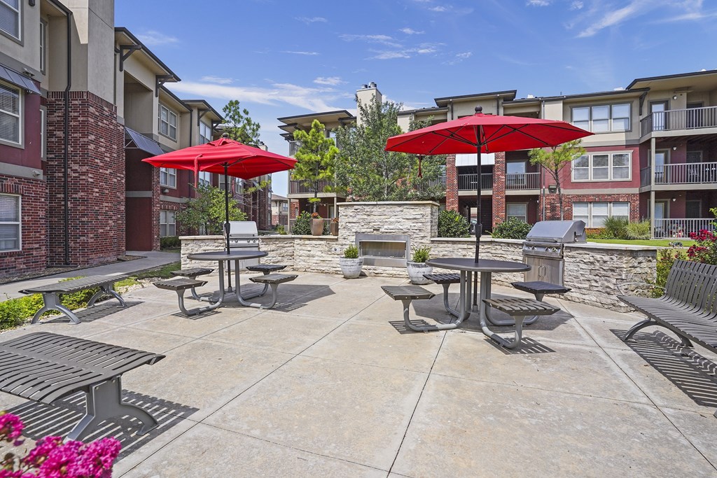 A patio with tables and chairs and umbrellas.