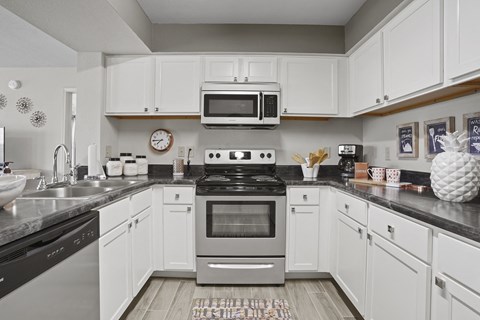 A modern kitchen with white cabinets and stainless steel appliances.