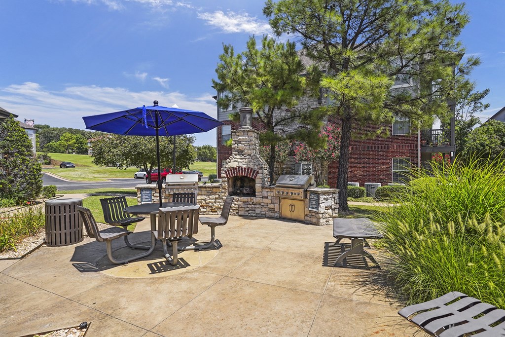 A patio with a table and chairs and a blue umbrella.
